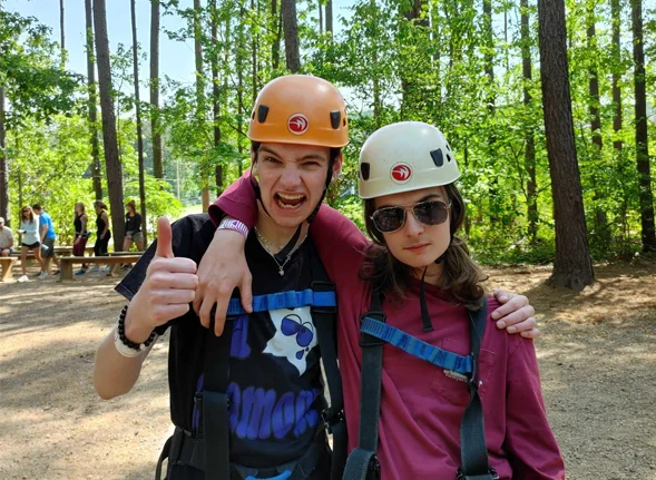 Two teens outside in wooded setting smiling and making silly faces