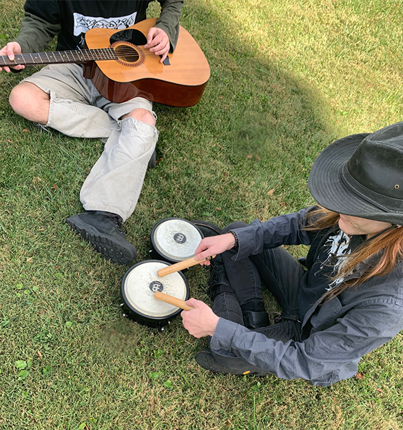 Visible guitar and bongo drums while people are playing musical instruments