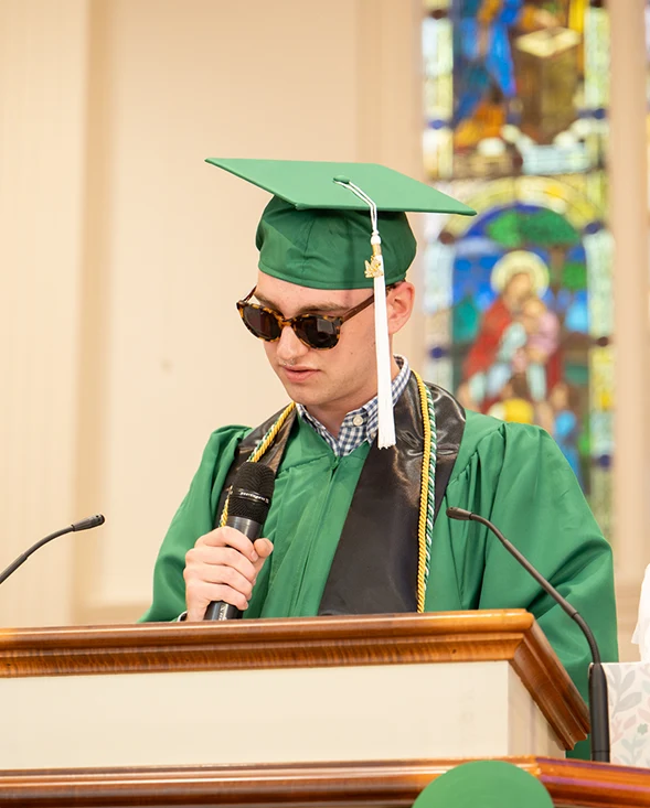 Student wearing sunglasses and giving speech at graduation