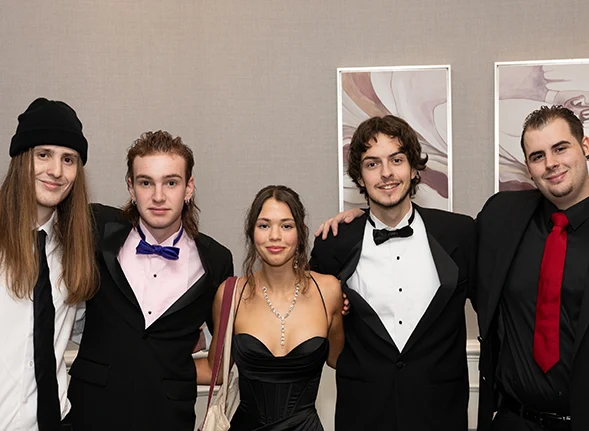 Emerald School Alumni wearing formal attire for gala locking arms and smiling.